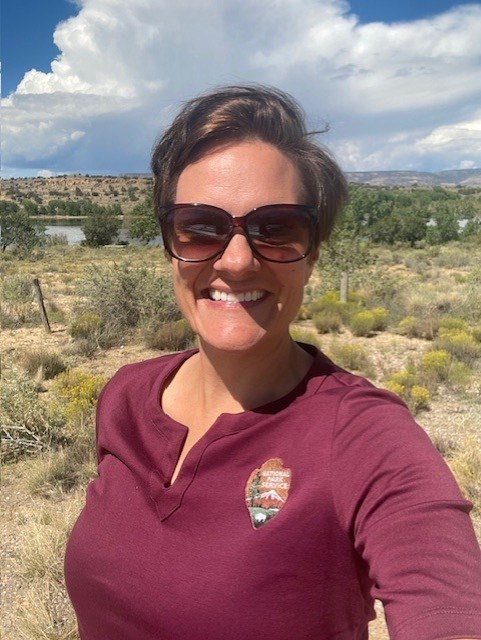 A woman with sunglasses smiling outdoors